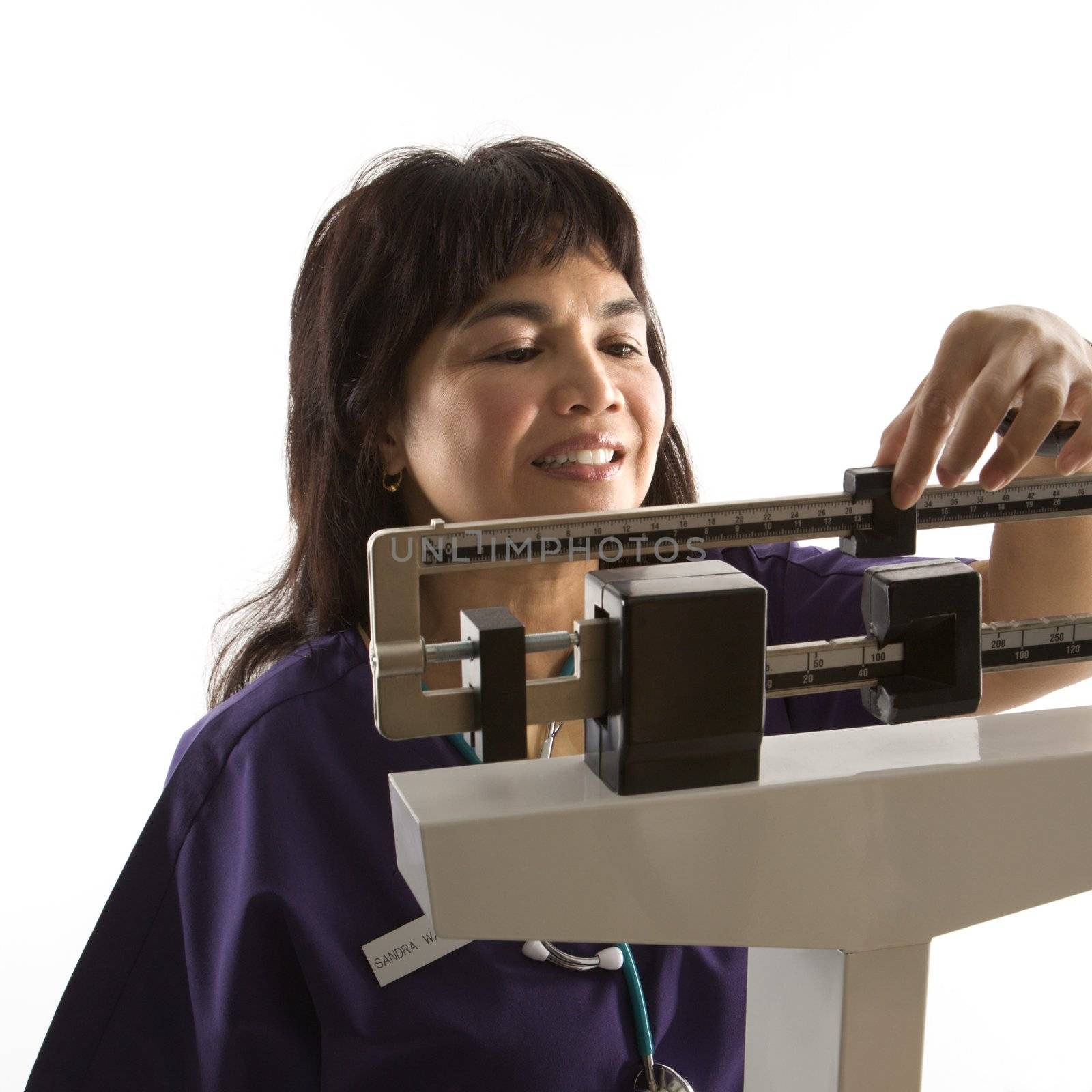 Middle-aged female Filipino nurse reading weight on scale.