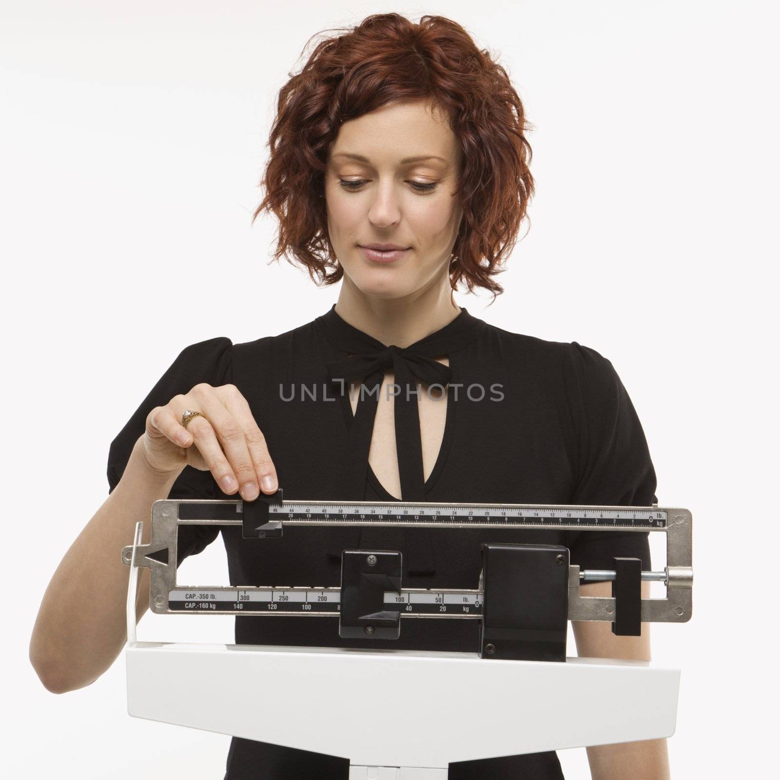 Pregnant Caucasian mid-adult woman reading her weight on scale.