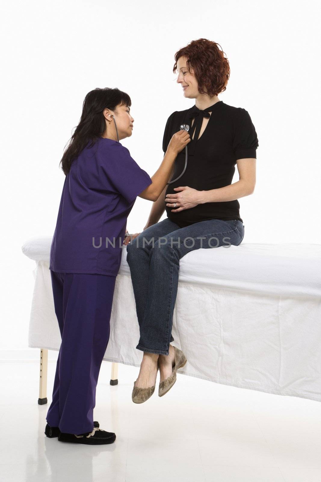 Pregnant Caucasian mid-adult woman having vital signs checked by nurse.