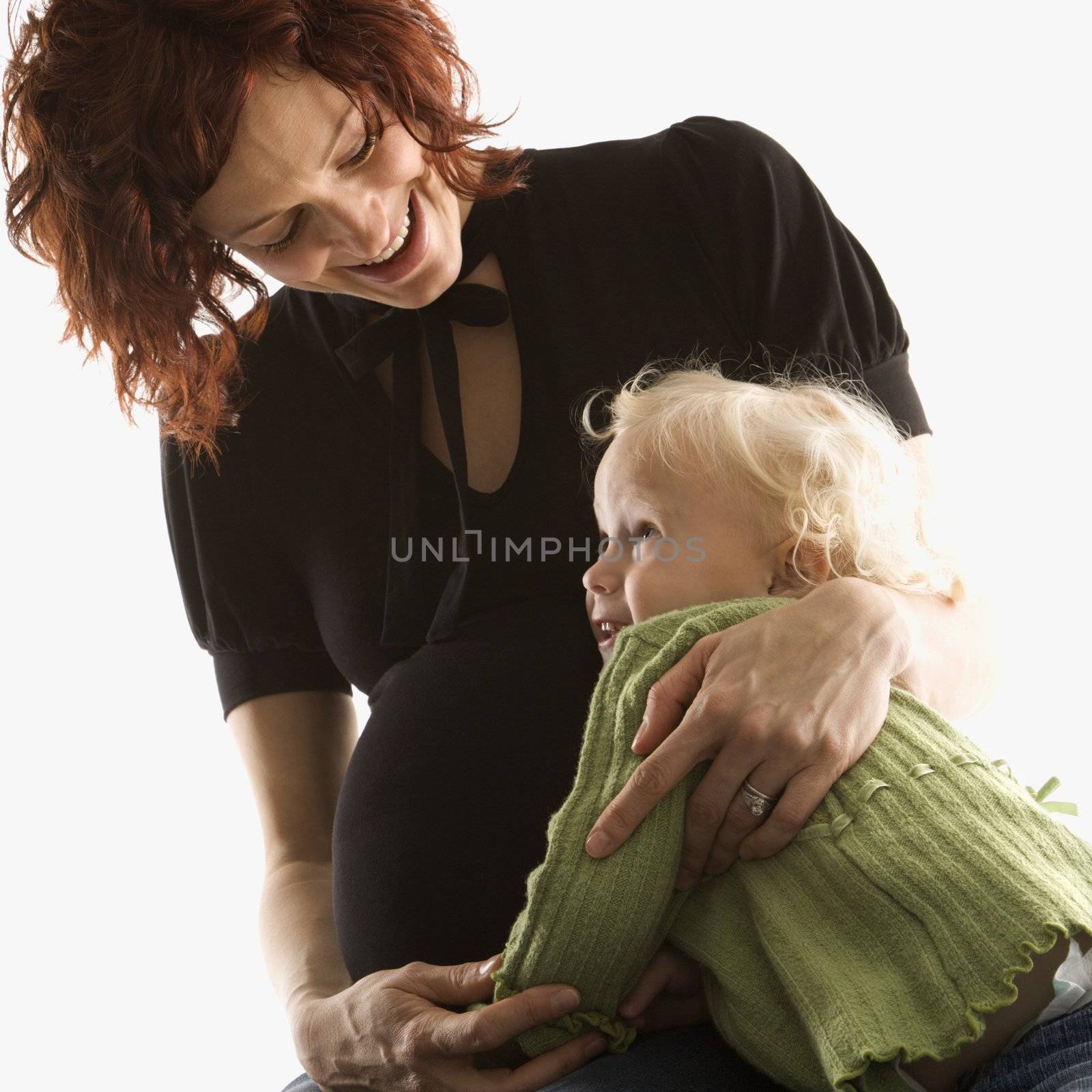Pregnant Caucasian mid-adult woman hugging her daughter.