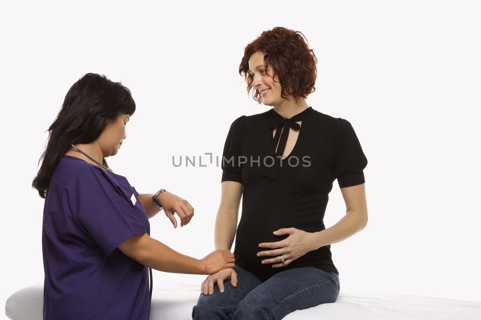 Pregnant Caucasian mid-adult woman having vital signs checked by nurse.