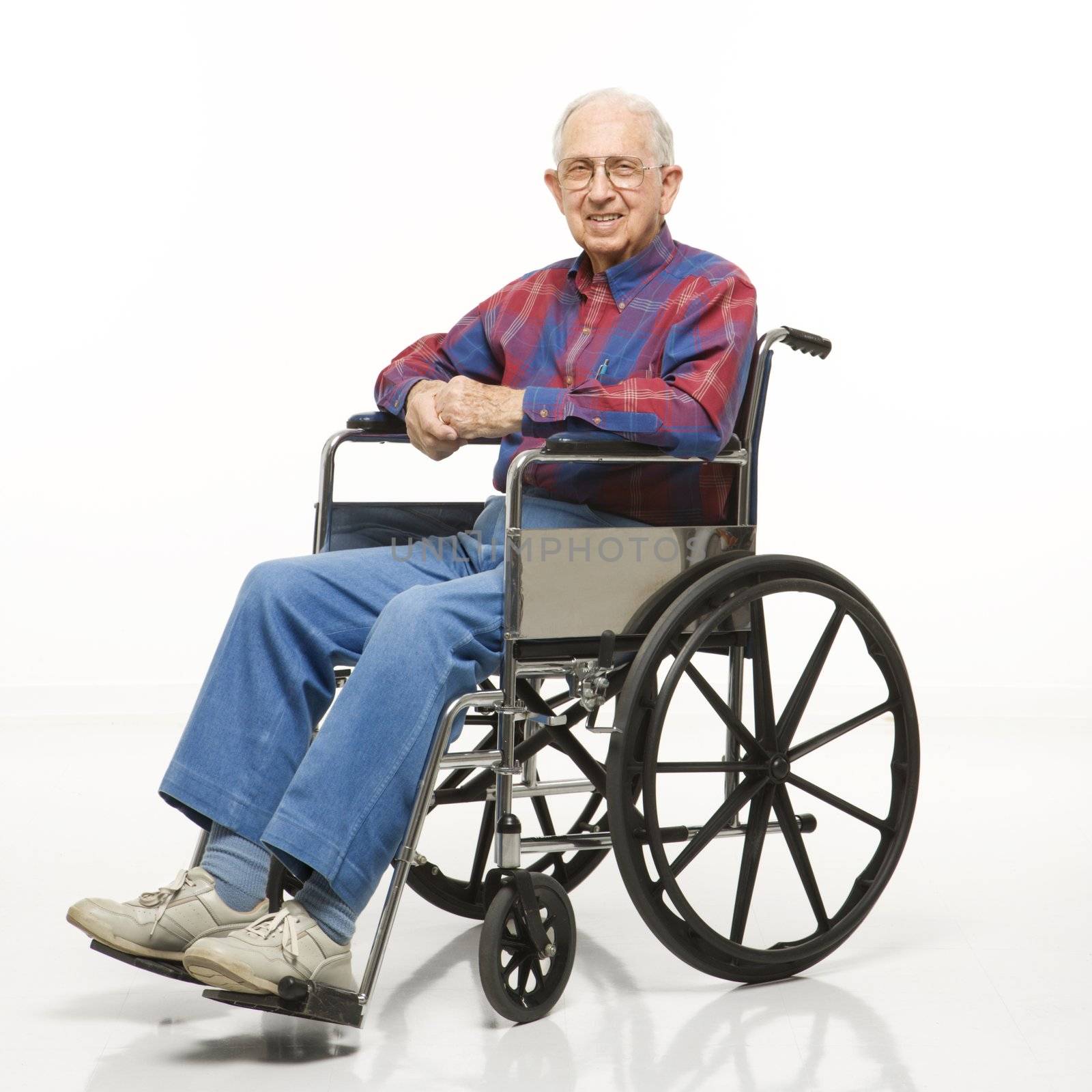 Portrait of Caucasion elderly man sitting in wheelchair smiling at viewer.