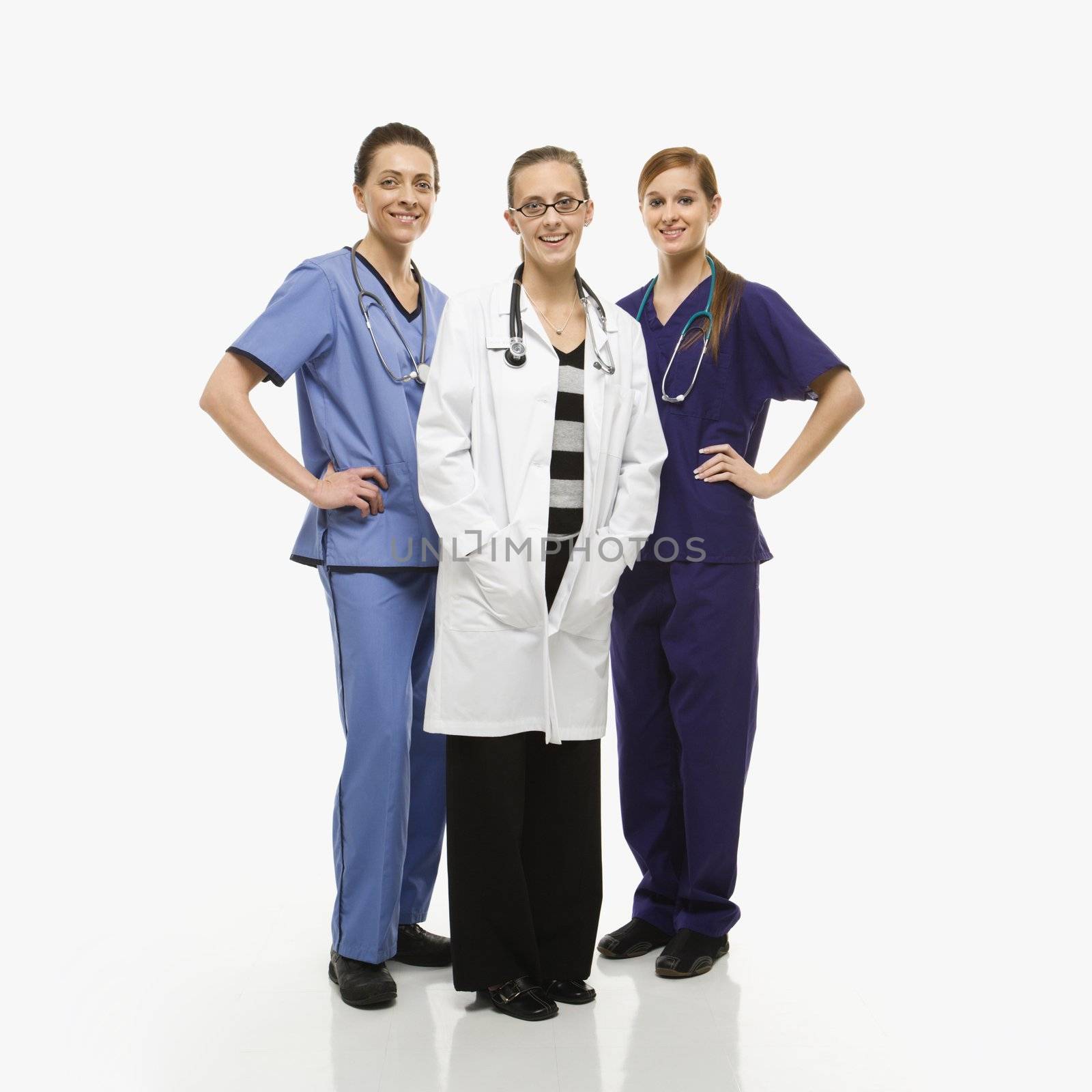 Portrait of smiling Caucasian women medical healthcare workers in uniforms standing against white background.