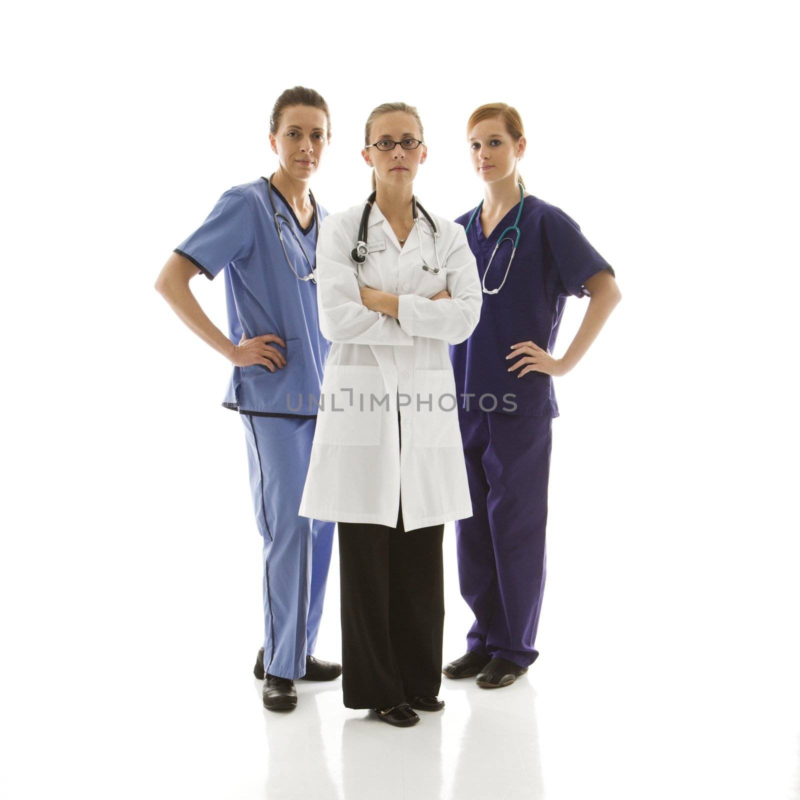 Full-length portrait of Caucasian women healthcare workers in uniforms standing against white background.