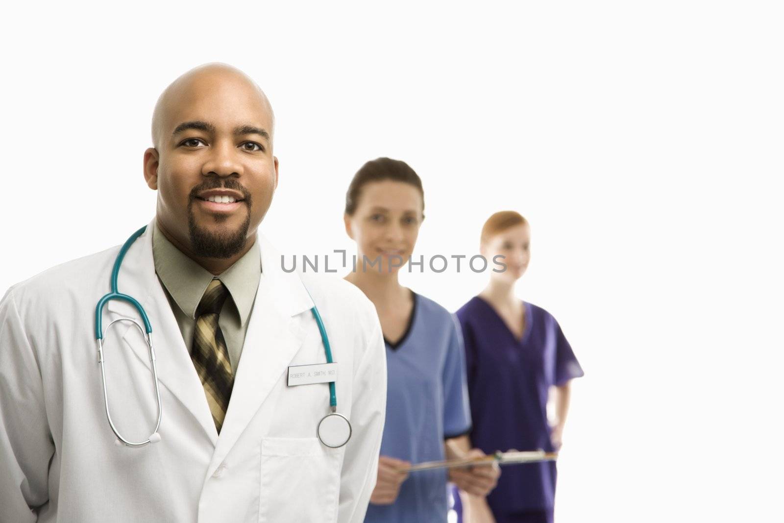 Portrait of smiling African-American man and Caucasian women medical healthcare workers in uniforms standing against white background.
