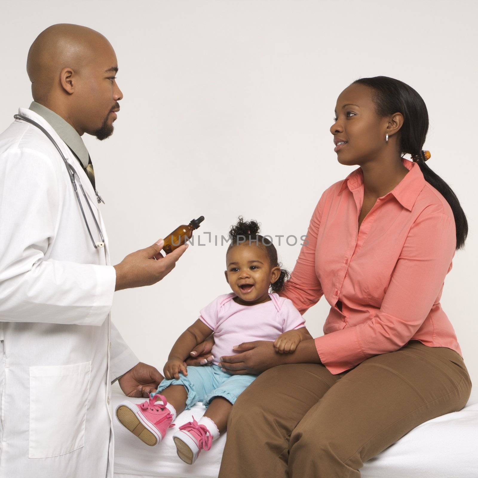 African-American mother and baby girl talking to male pediatrician.