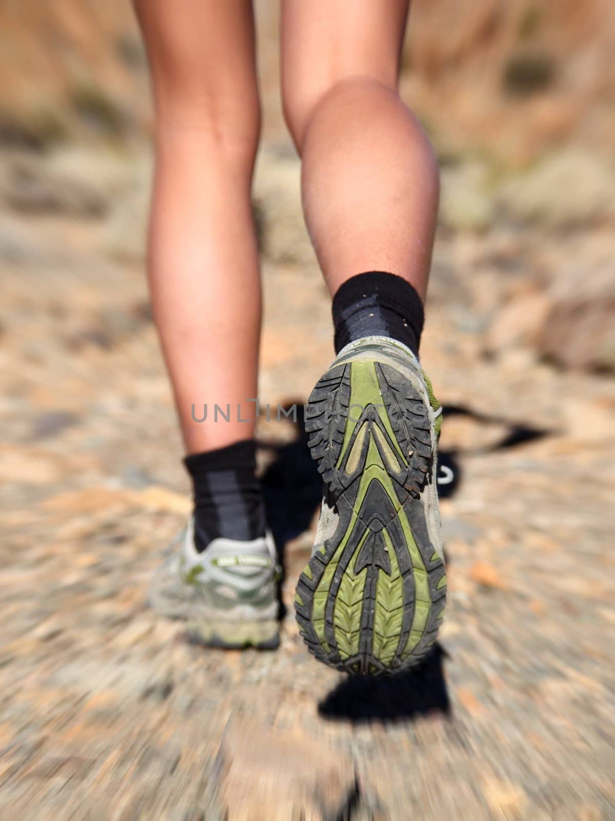 Woman running on trail in desert. Zoom motion blurred closeup shoes of woman trail running in desert.