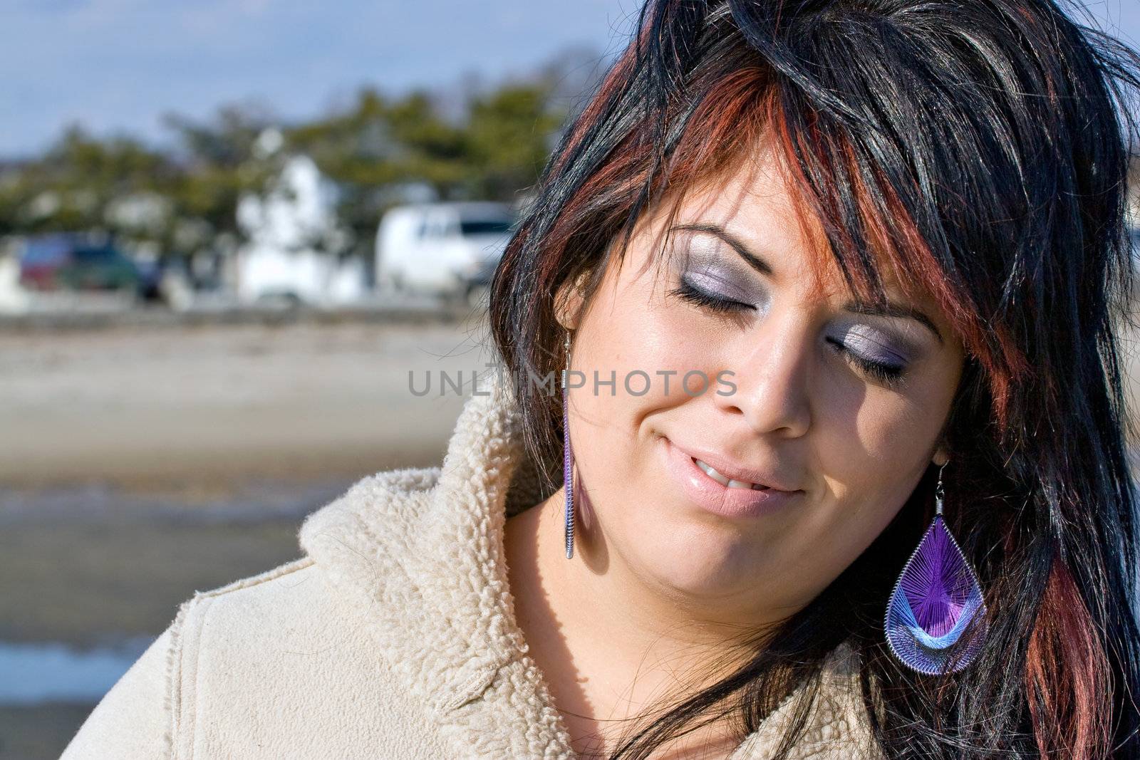 A young Hispanic woman soaking up some Vitamin D from the warm sunlight at the beach.