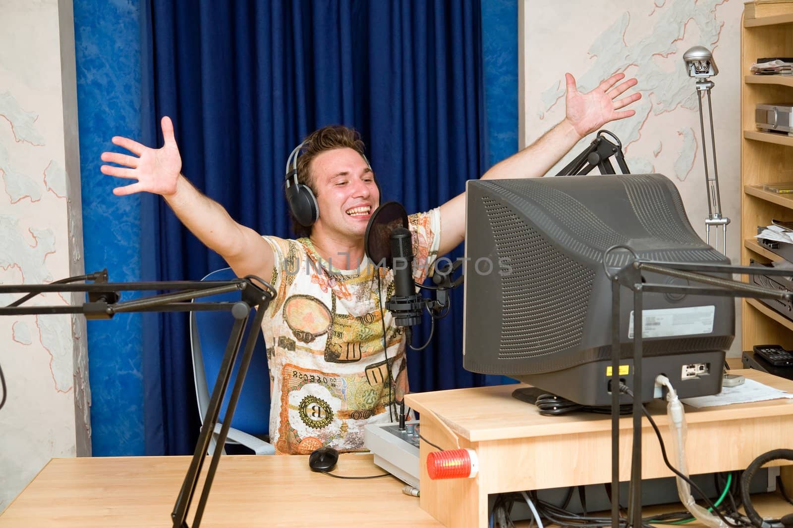 Radio DJ.  Smiling young man with microphone and big headphone.