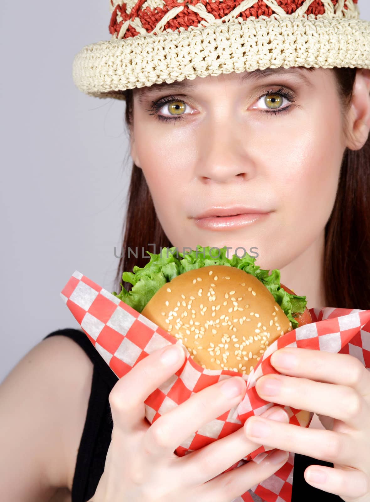 woman with a hat holding a hamburger