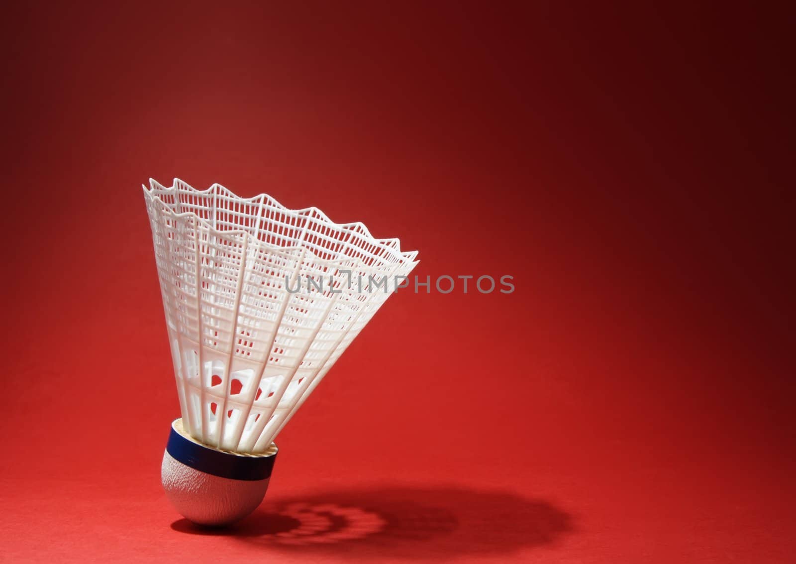 nylon badminton shuttlecock with its shadow, red background