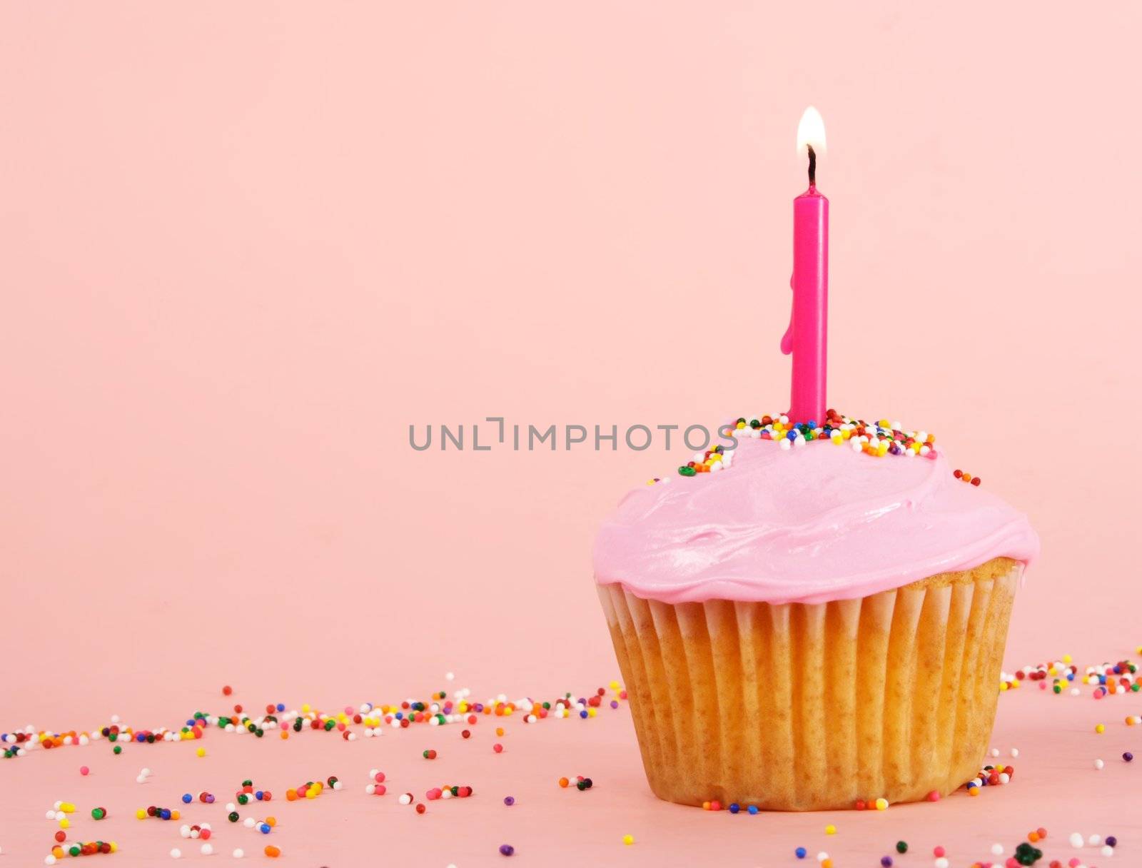 homemade cupcakes with pink icing and candle