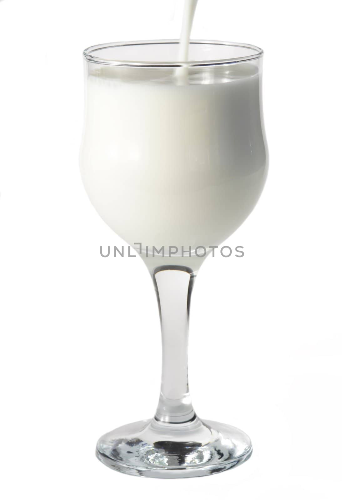 pouring some fresh milk in a wine glass, isolated on white