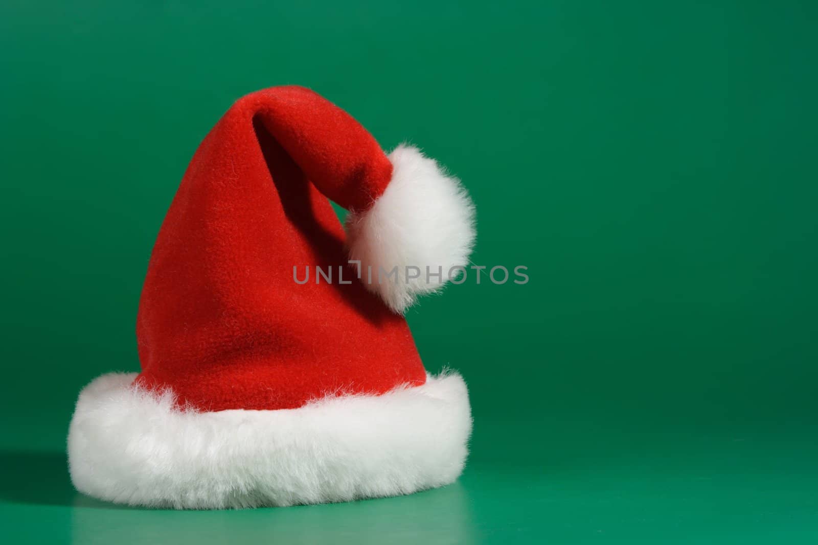 Red and white christmas hat on green background