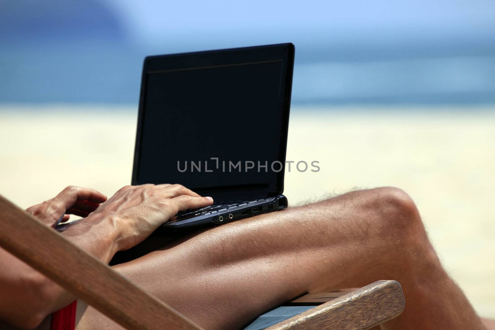 The man in an armchair with a computer on a dark blue ocean beach