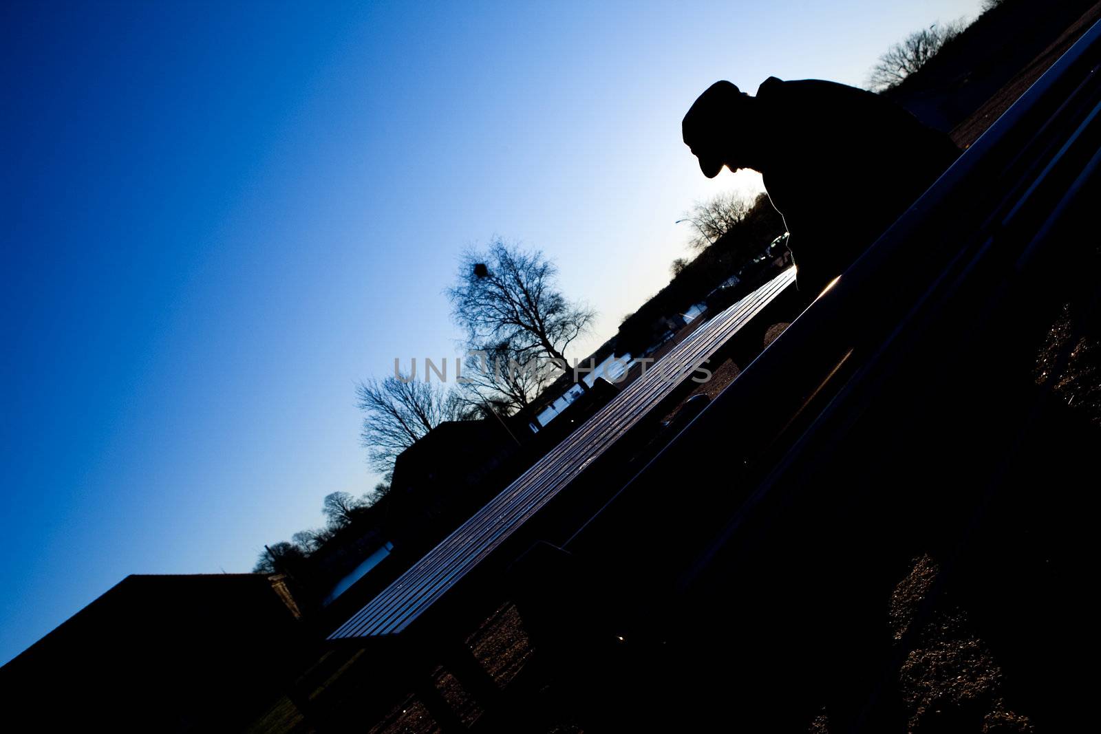 A depressed thoughtful sitting on a park bench in cold winter scene.