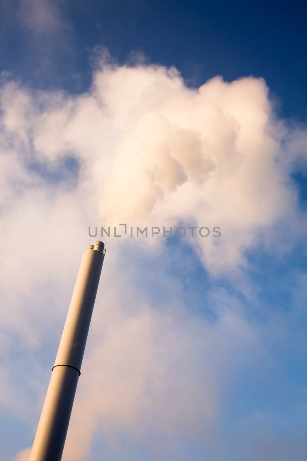 A smoke stack polluting into a blue sky