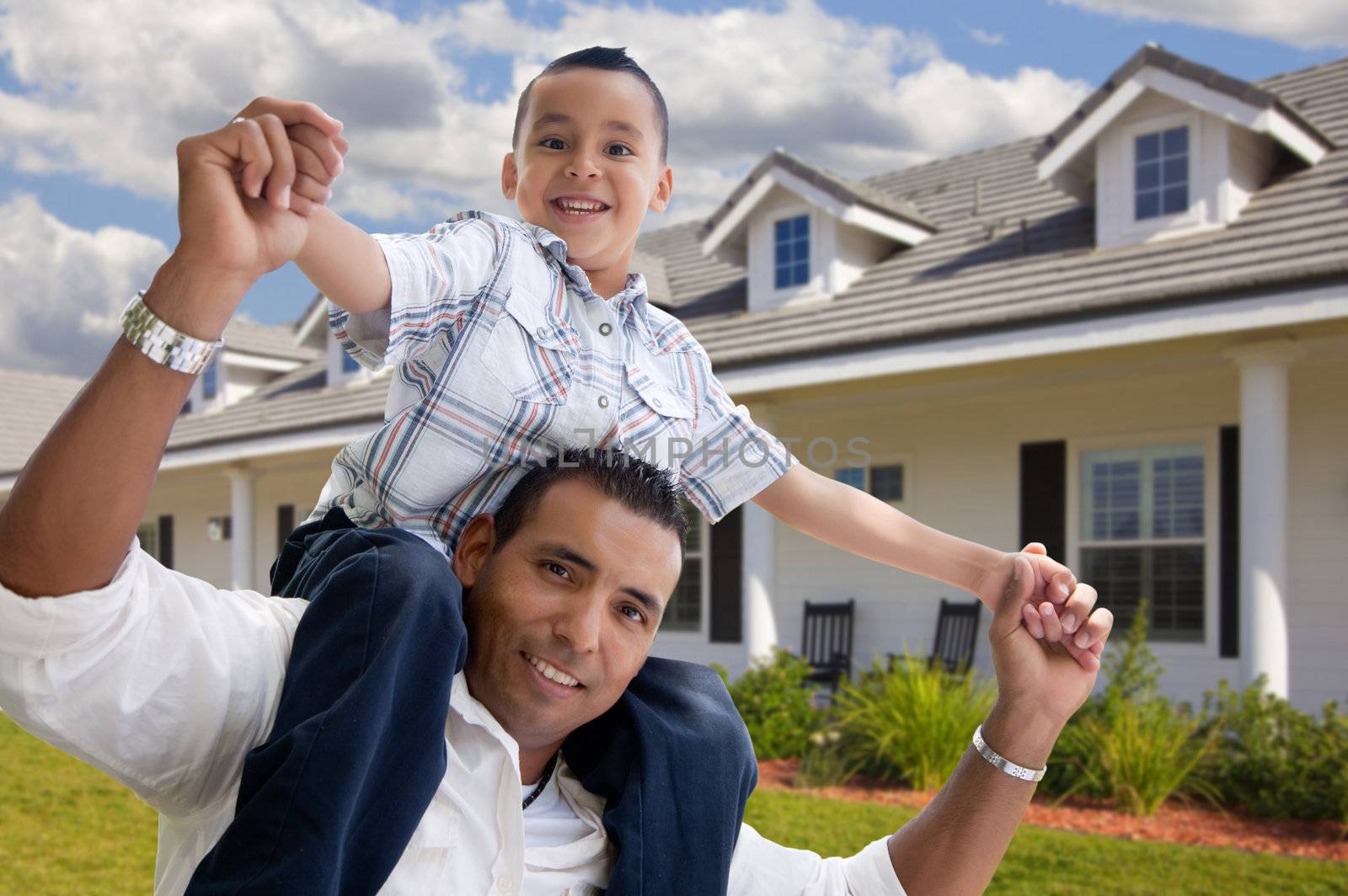 Playful Hispanic Father and Son in Front of Beautiful House.