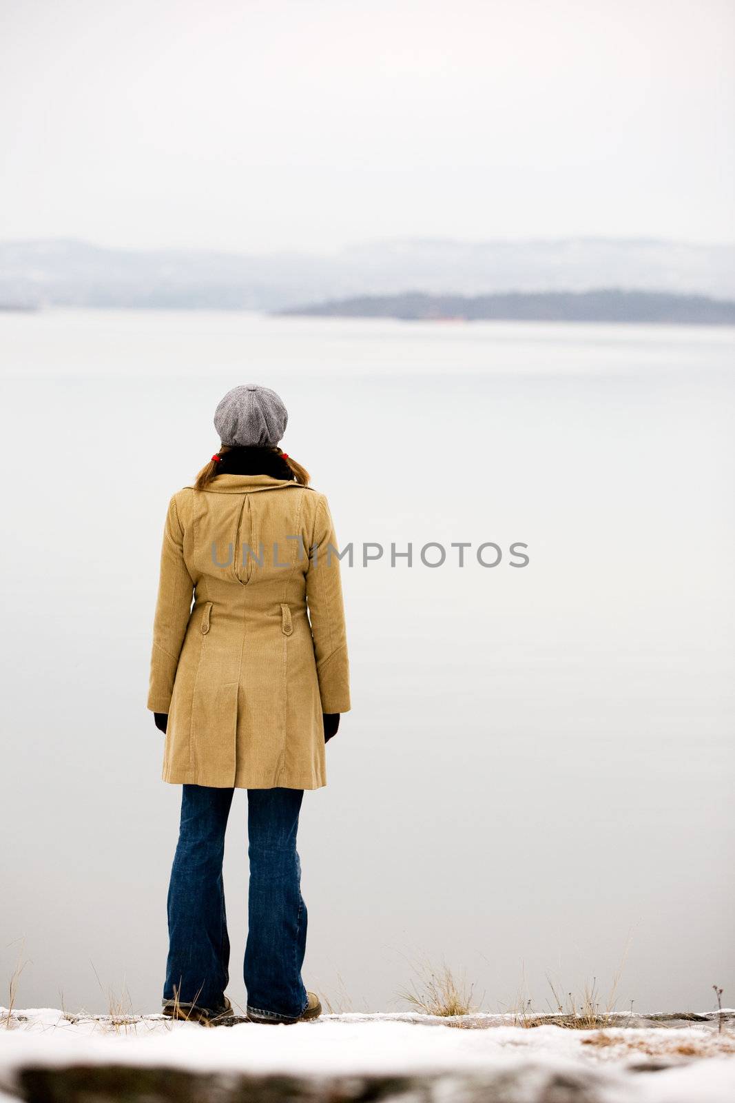 A young woman standing by the ocean in winter