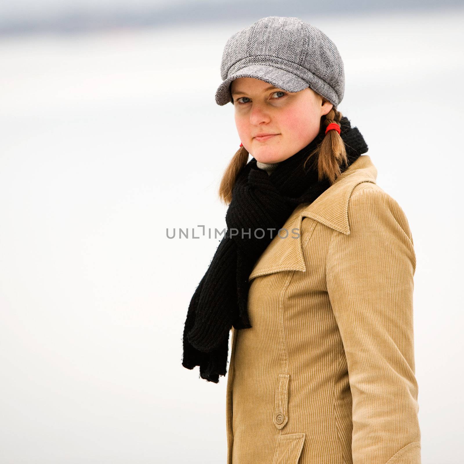 A young woman standing by the ocean in winter