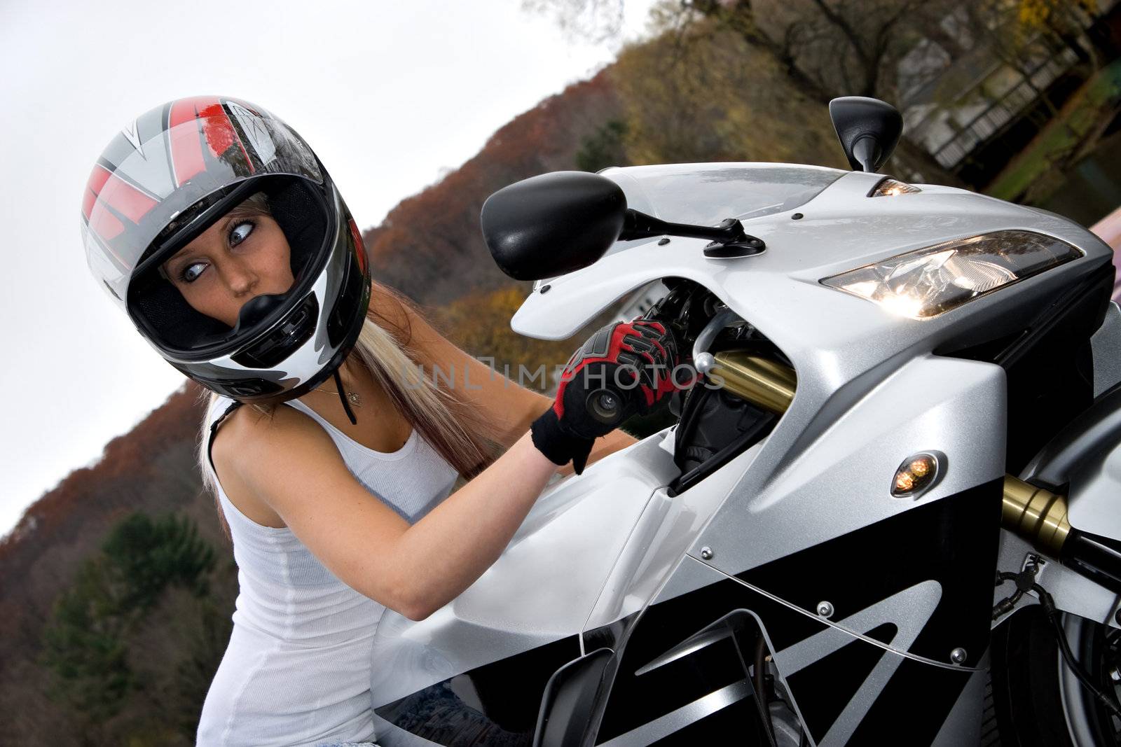 A pretty blonde girl seated on a modern motorcycle.