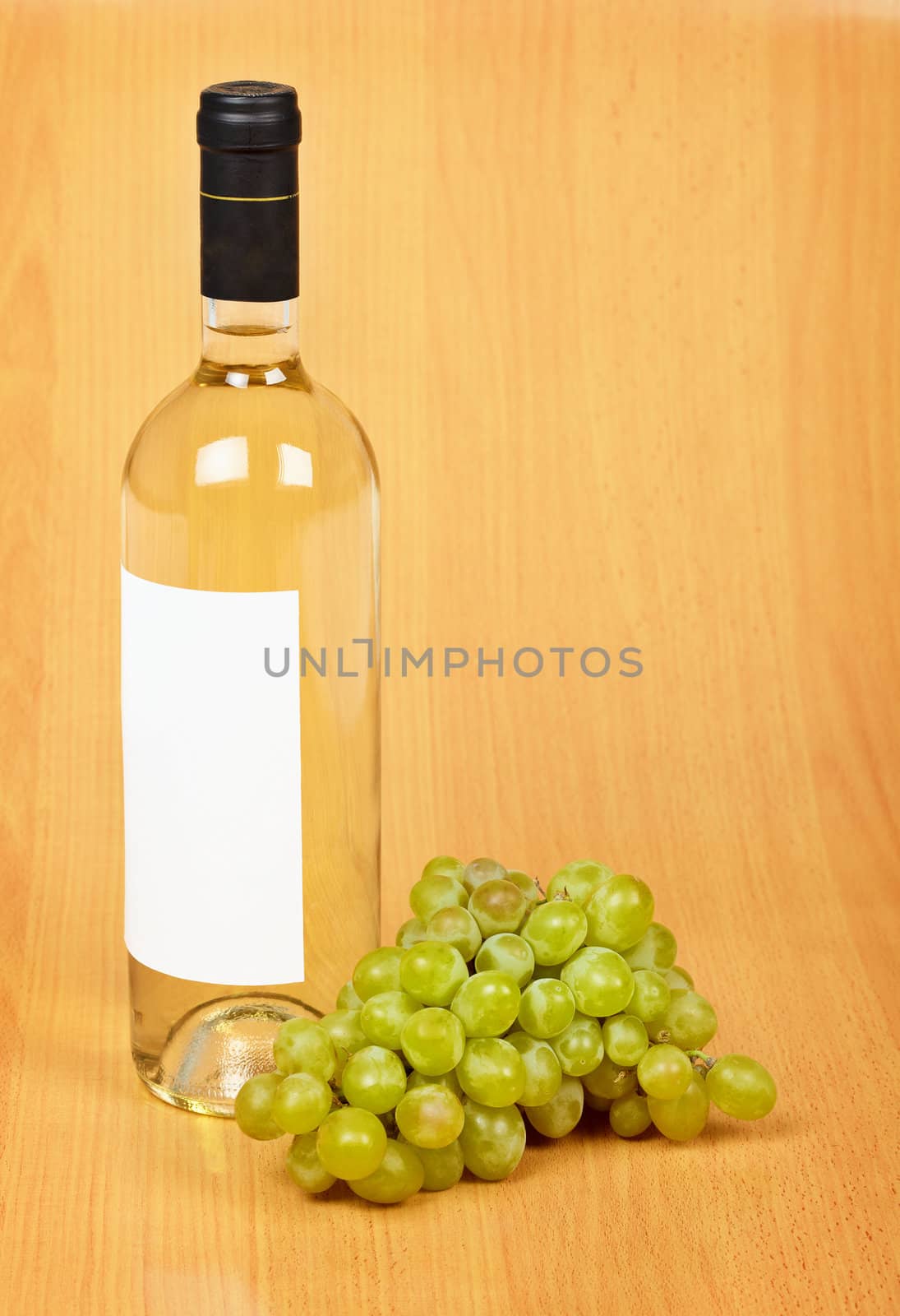 A bottle of white wine and bunch of grapes