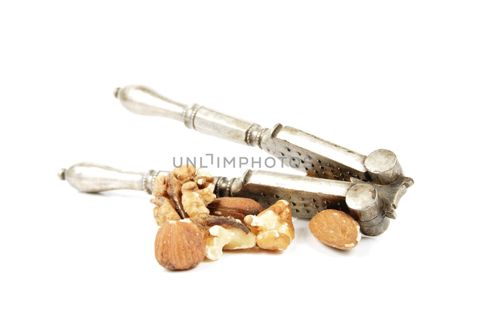 Assorted mixed nuts with a silver nutcracker on a reflective white background