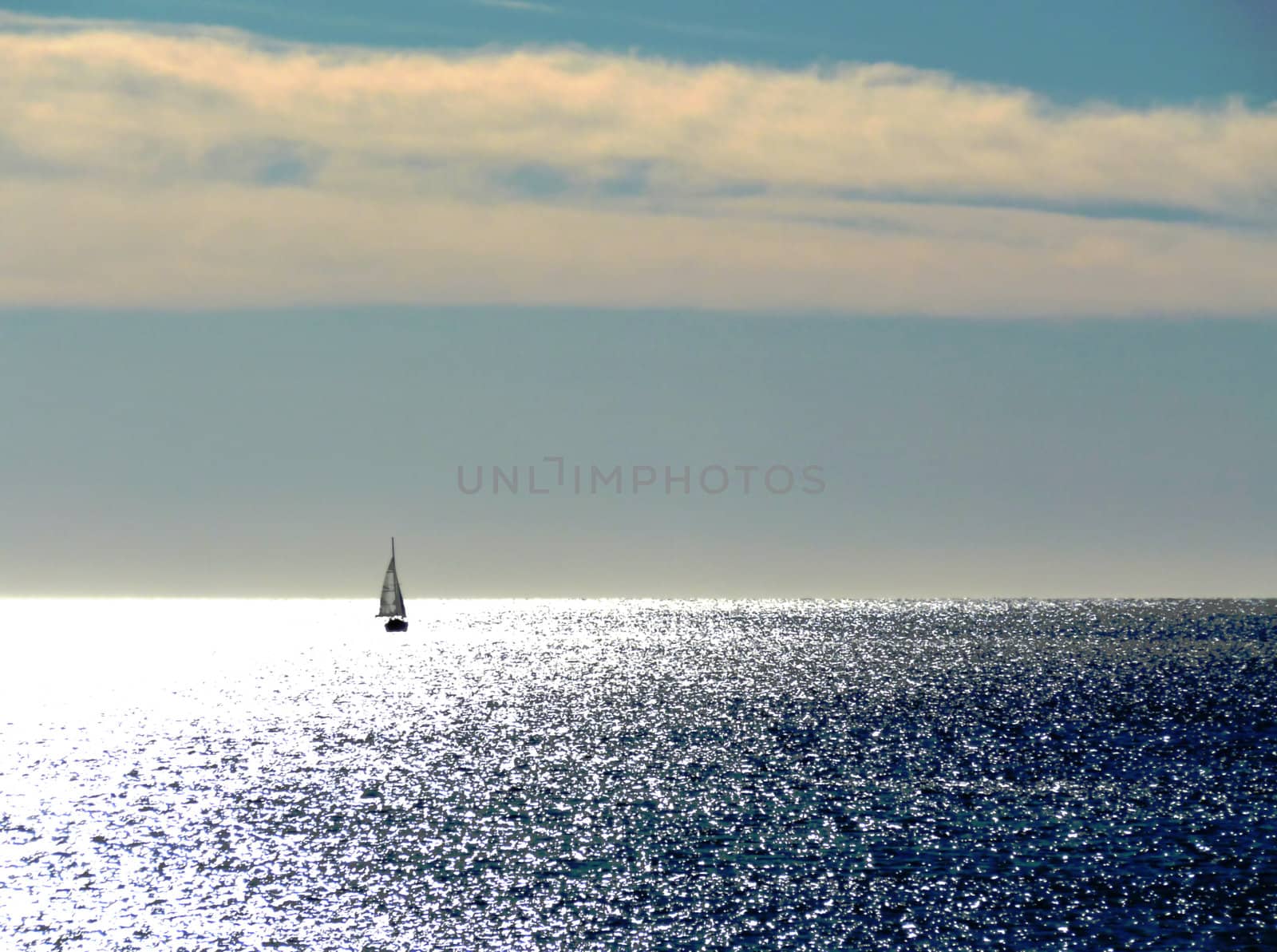 Small sailing boat on the mediterranean sea enlightened and pink clouds
