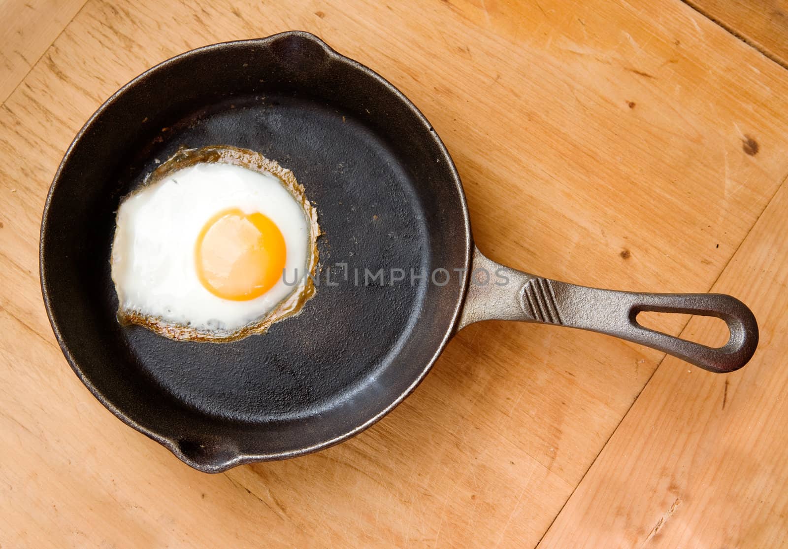 Detail image of a fried egg on a cast iron frying pan viewed from above