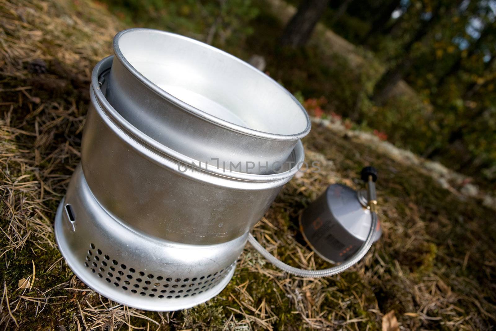 A camp stove cooking water in the forest with pressurized gas