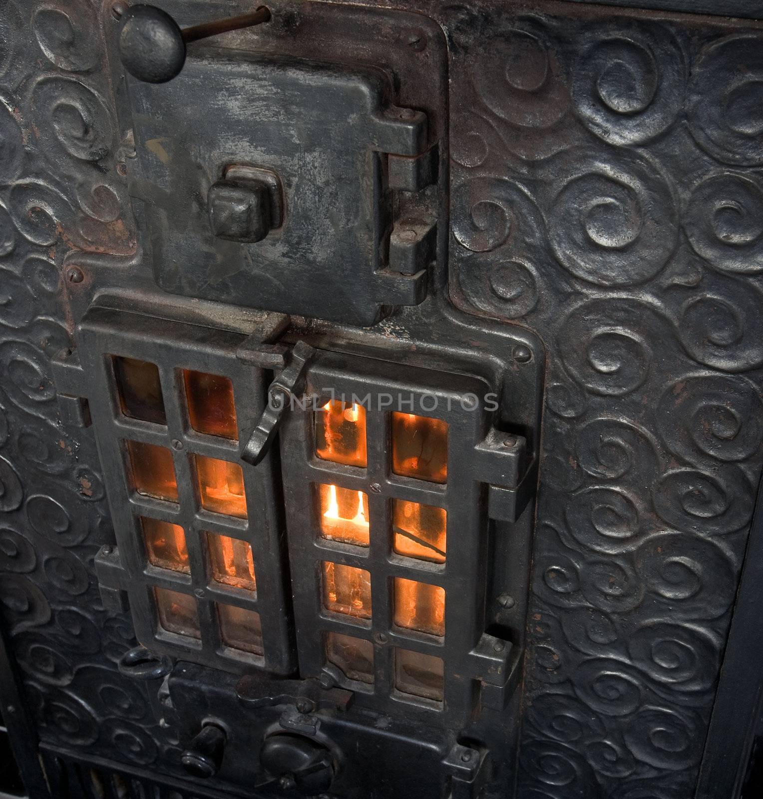 An old cast iron oven with flames viewable through the window