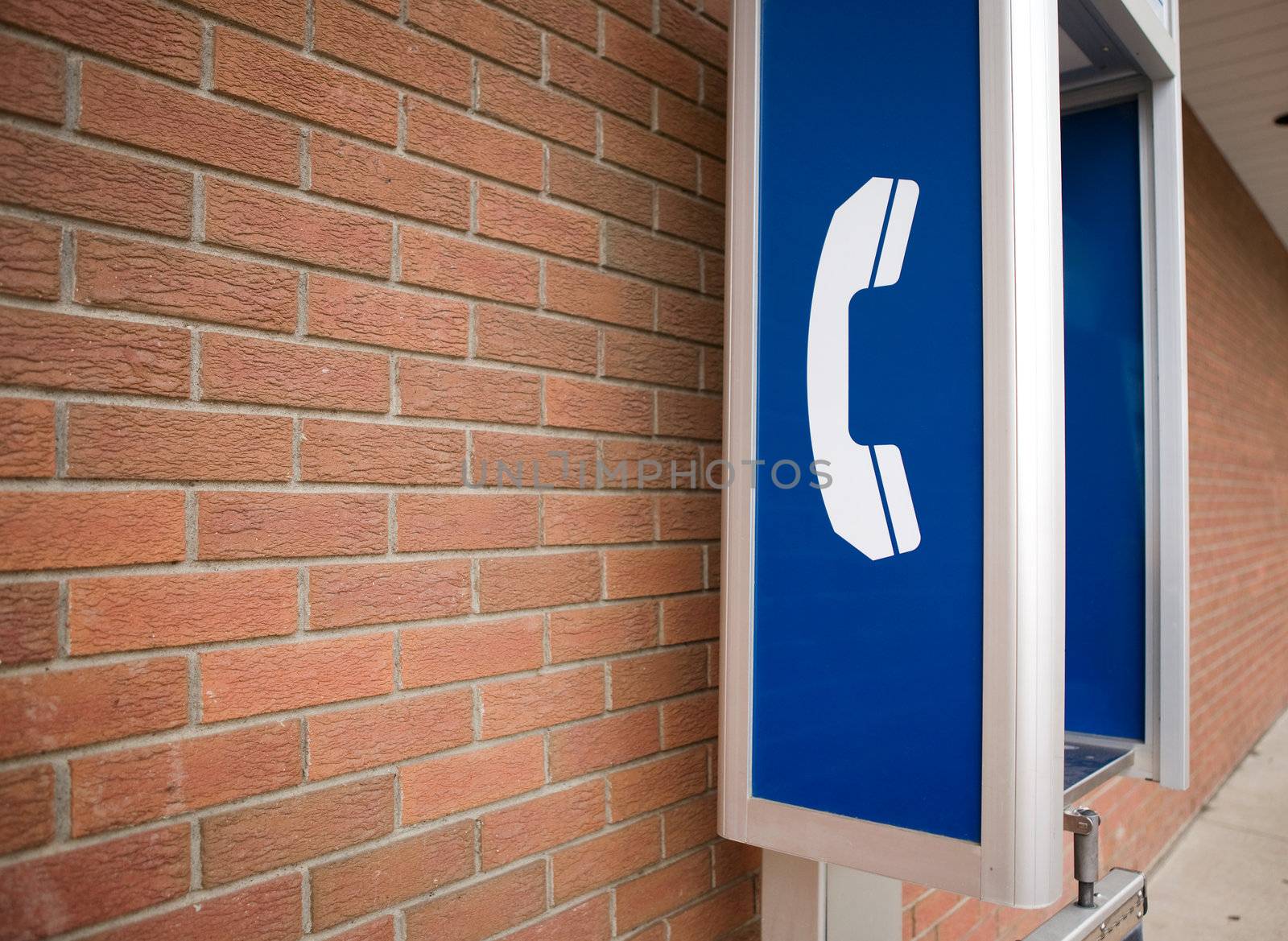 A pay phone against the side of a brick building