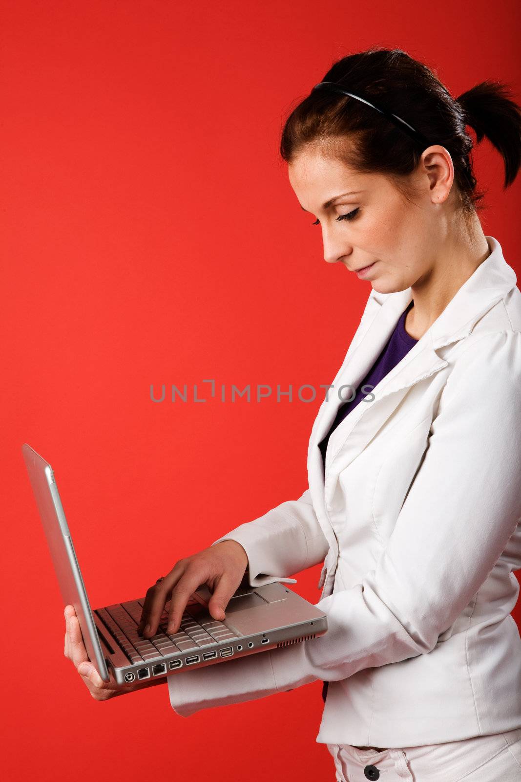 A young business woman or student using a laptop with a strong red background