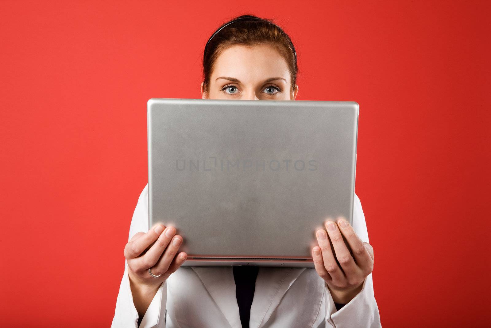 A young woman hiding behind and using a laptop computer wirelessly
