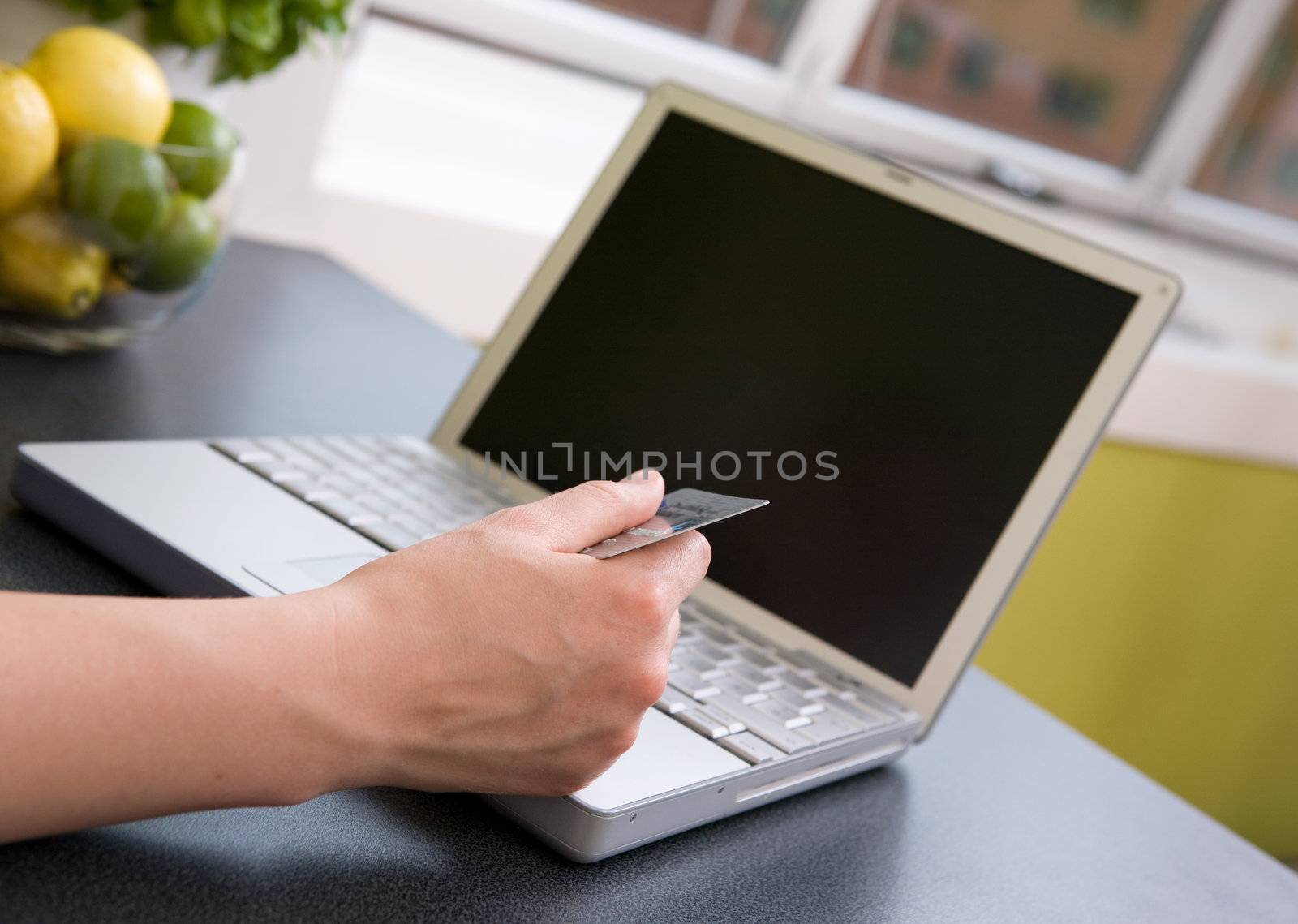 A young female making an online purchase from her kitchen.