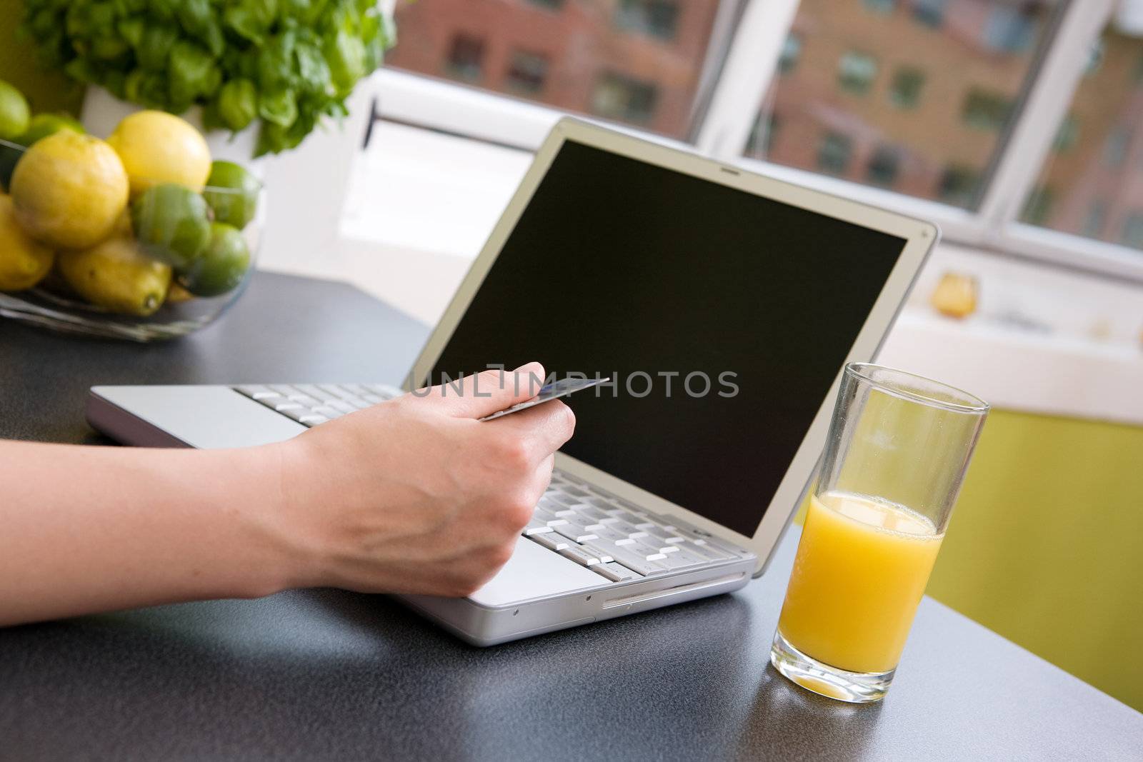 A young female making an online purchase from her kitchen.