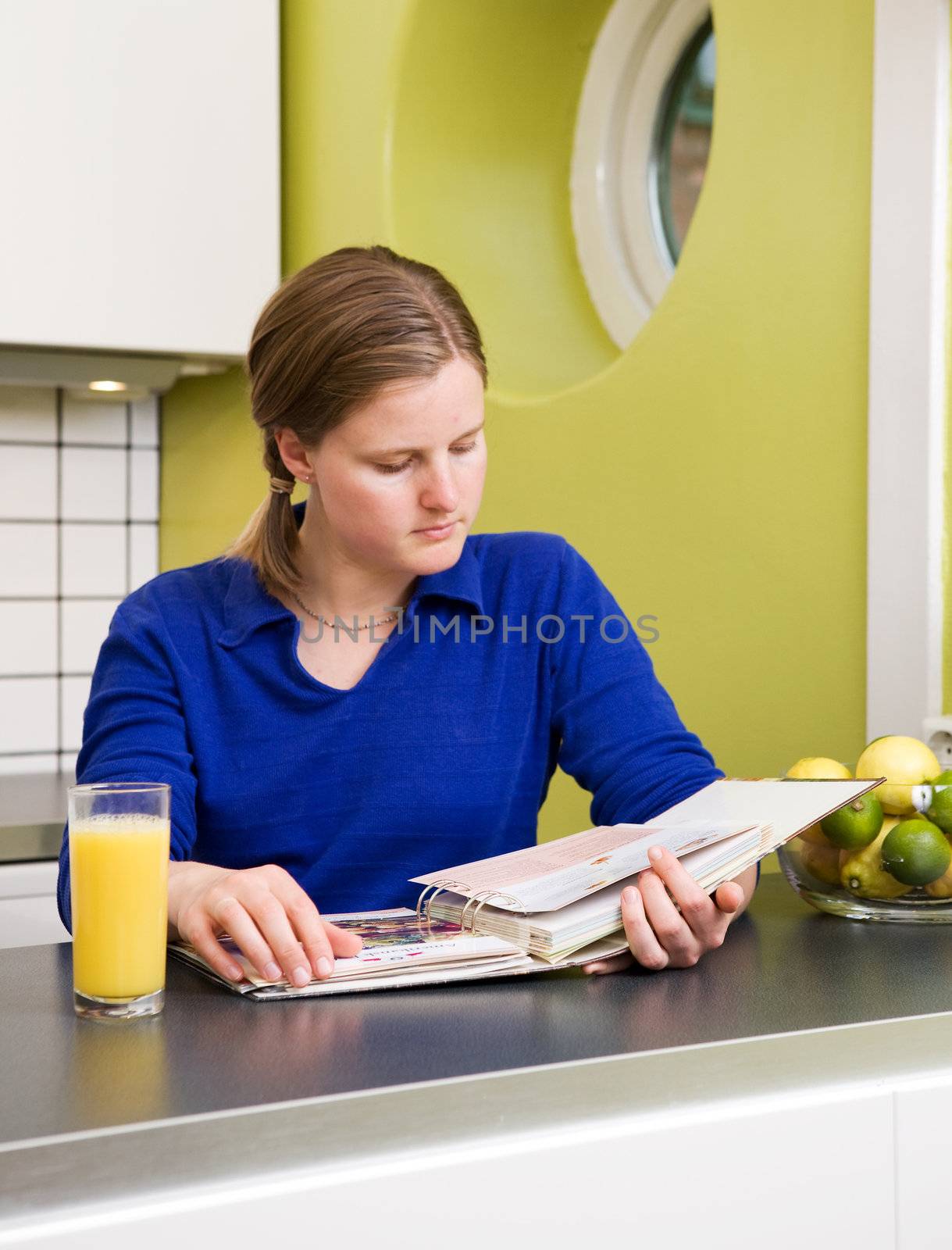 A young woman in the kitchen looking at recipes.