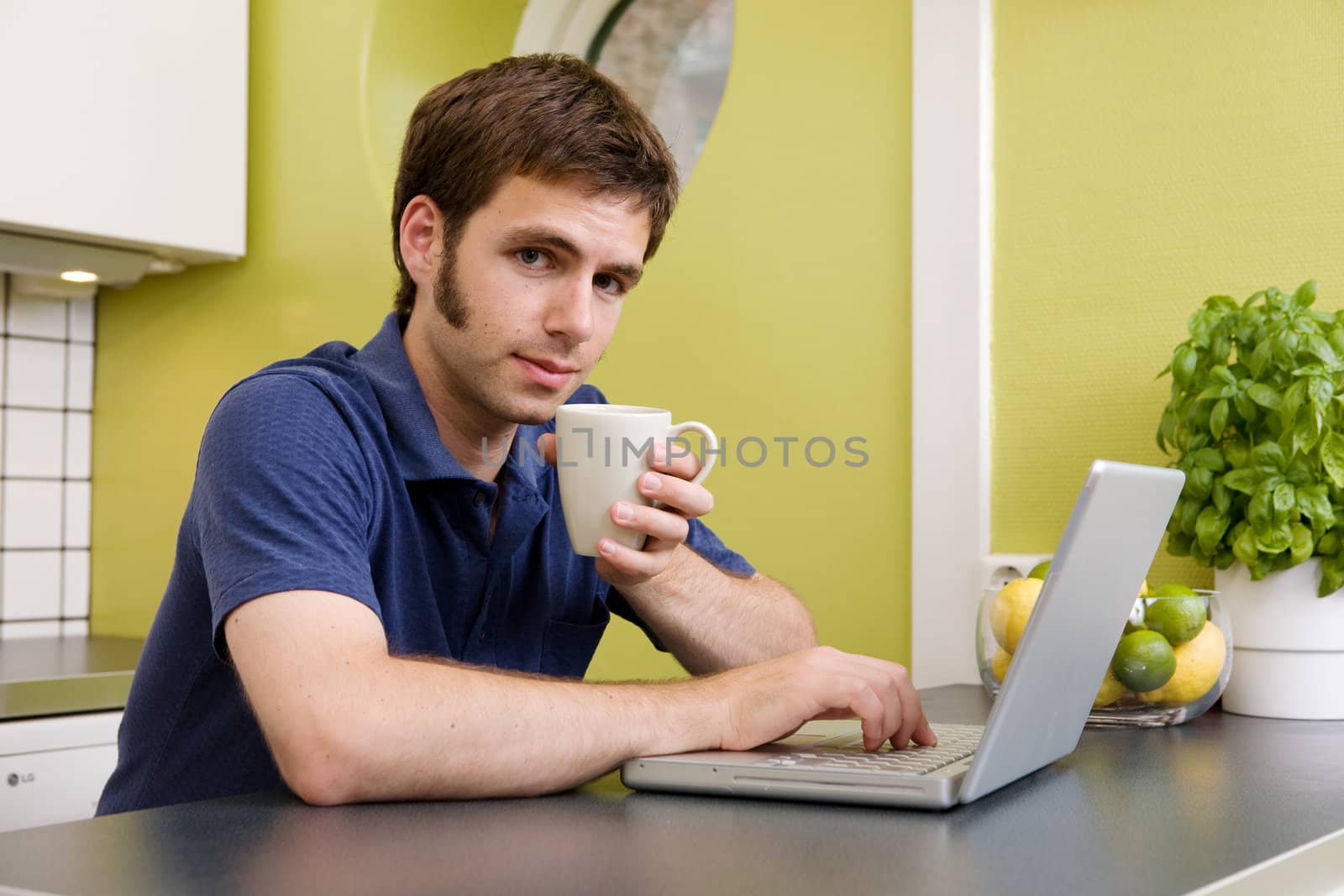 Young Man with Warm Drink at Computer by leaf