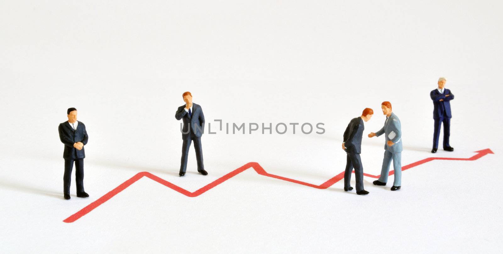 Group of managers (model railroad figures) positiones around graph showing rising development