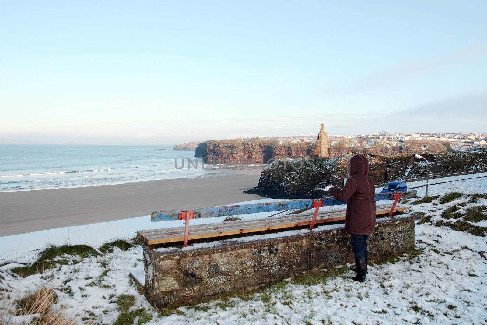 young girl at bench in winter with view of beach and cliffs