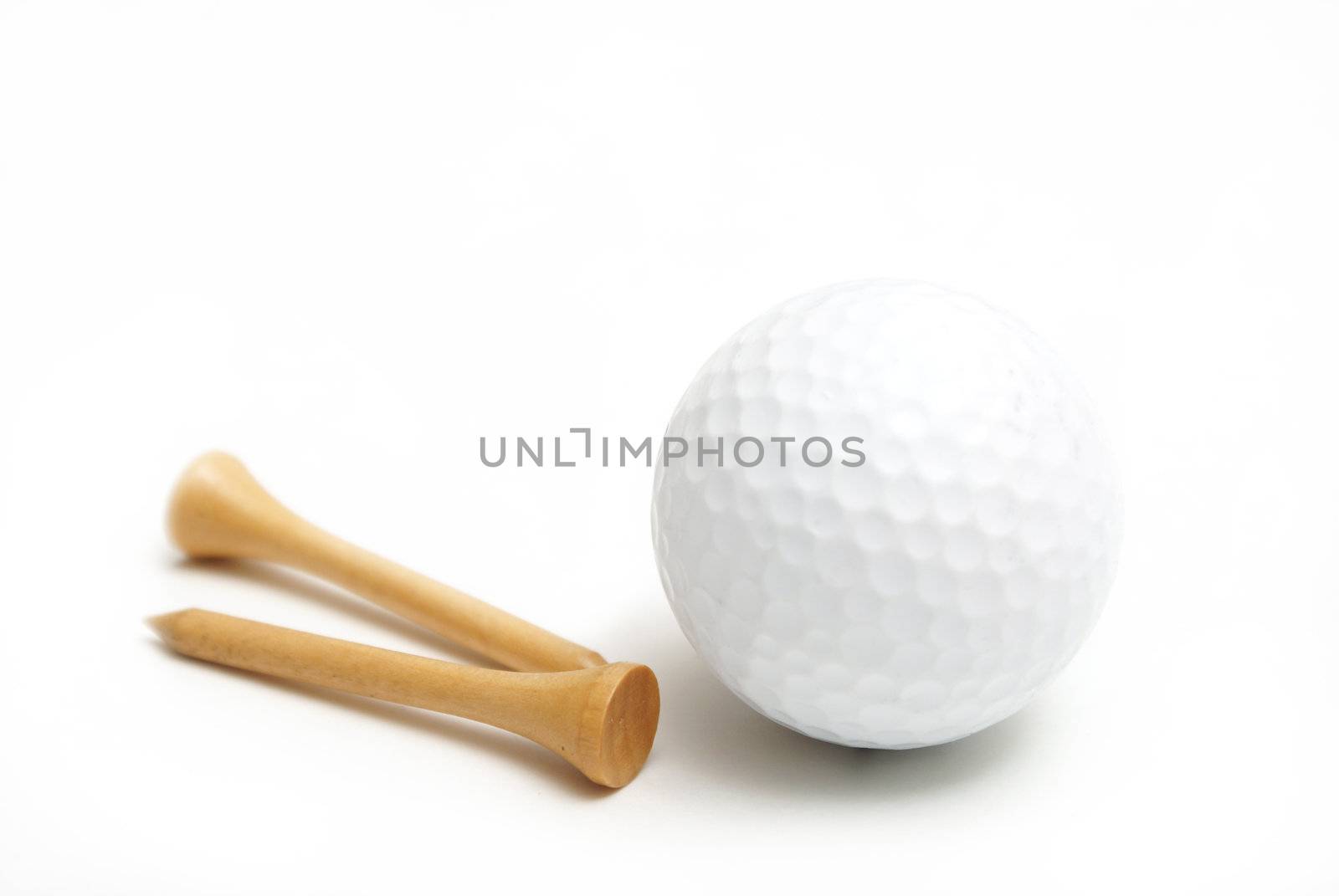 A golf ball and wooden tees are isolated over white.