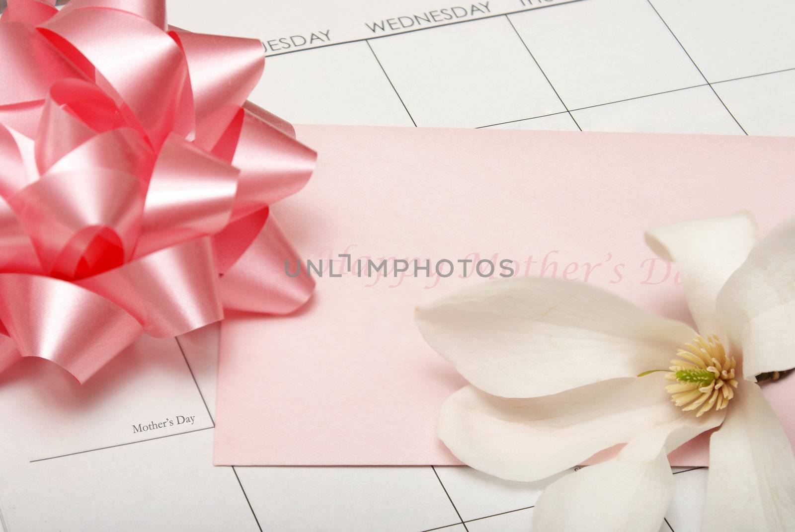 A card for mother lays on a calendar with other accesories for the celebration.