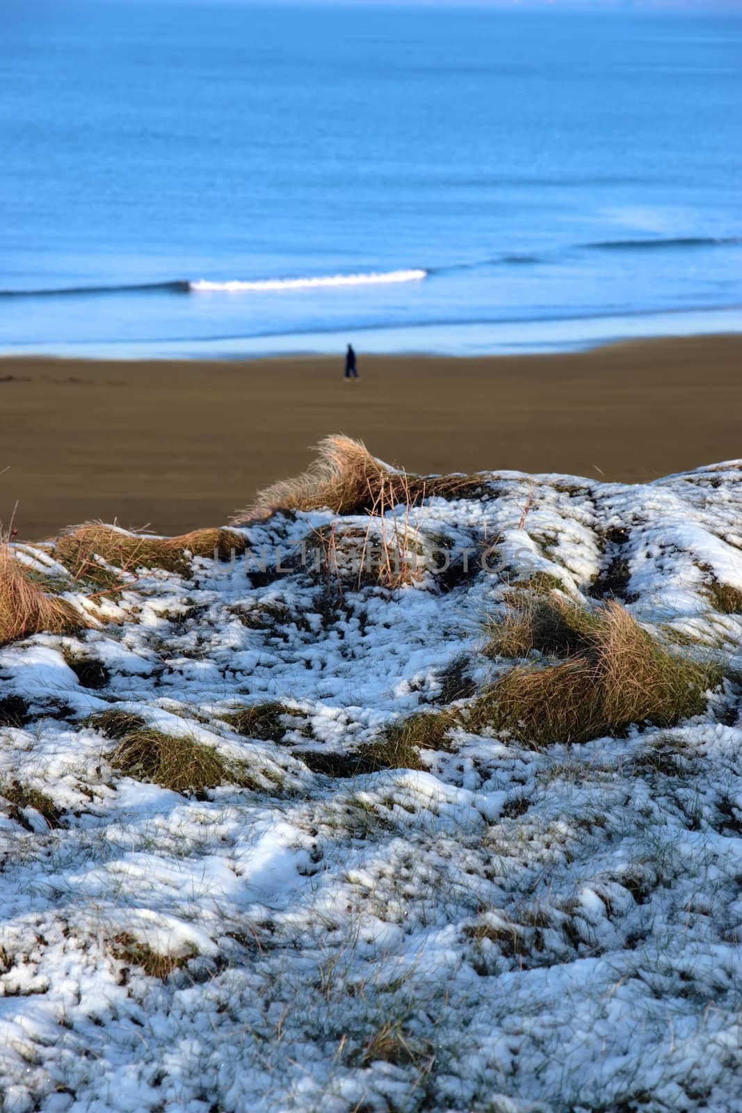 a lone person walking a beach on a cold winters day