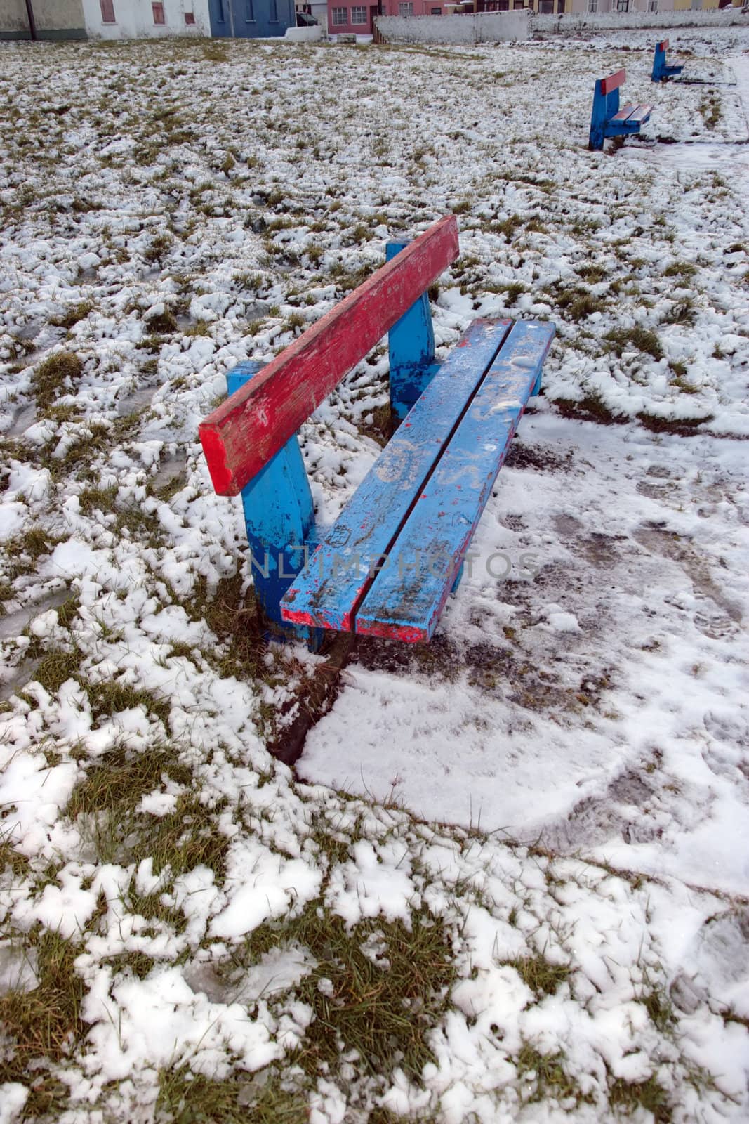 three benches beside a snow covered park footpath
