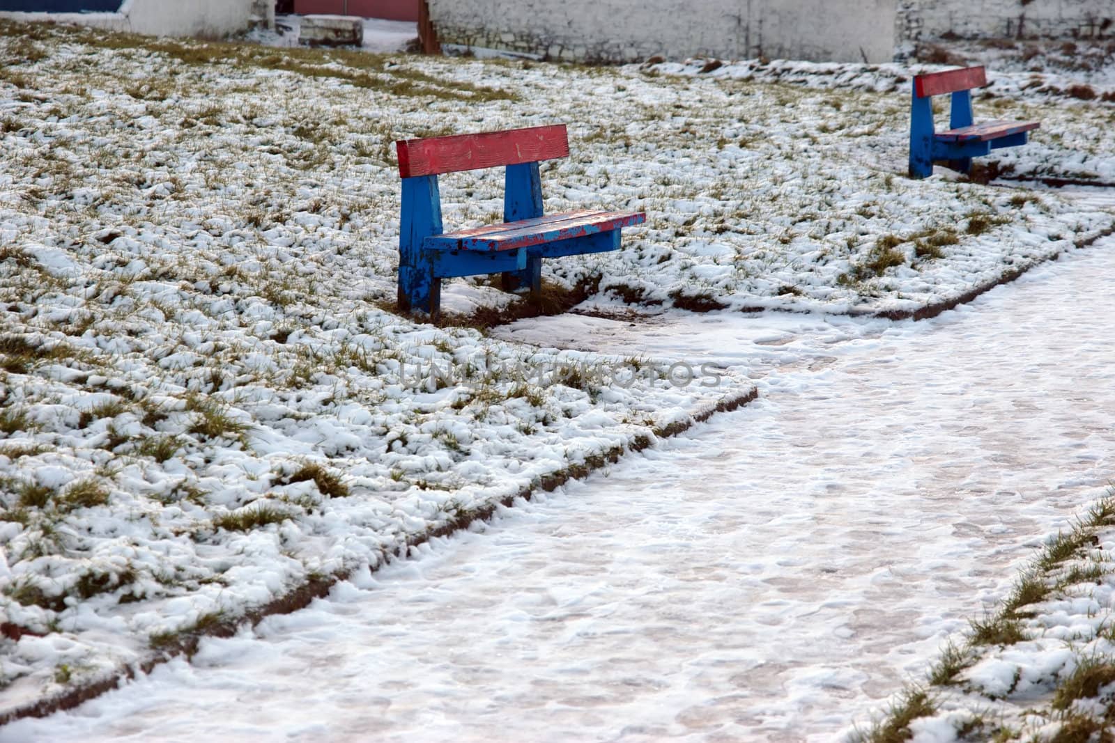two benches beside a snow covered park footpath