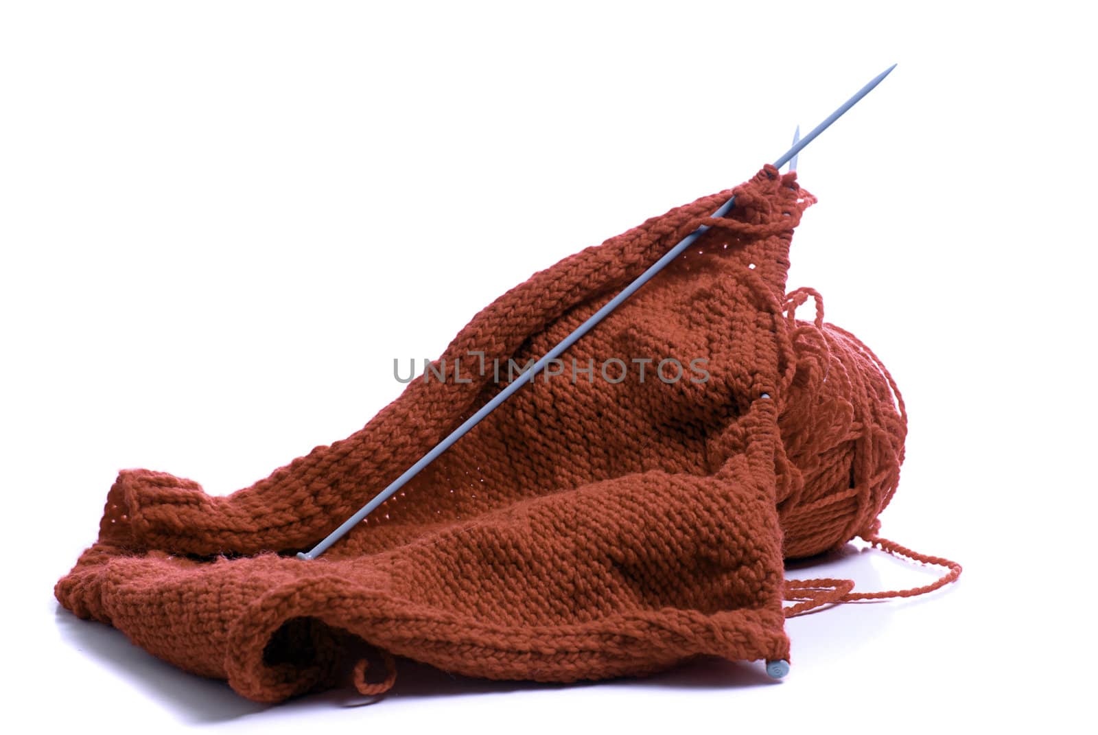Red yarn and knitting needles, isolated against a white background