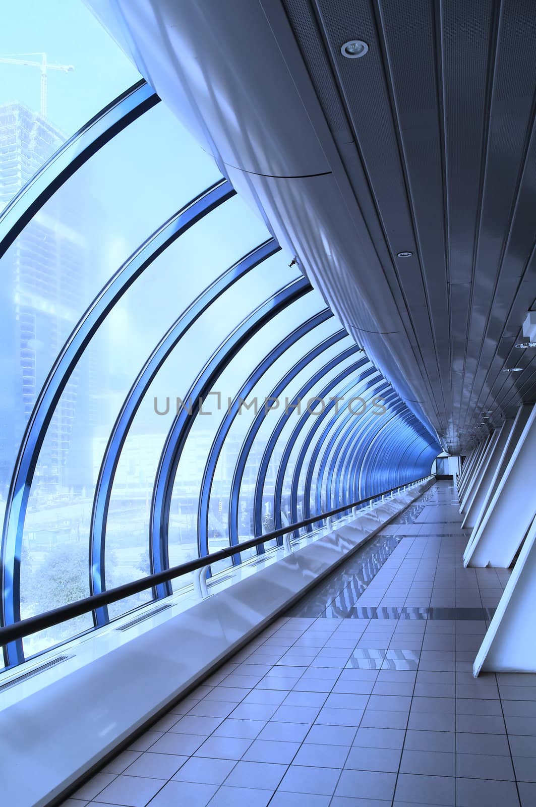 Blue tinted image of glass corridor in modern office centre