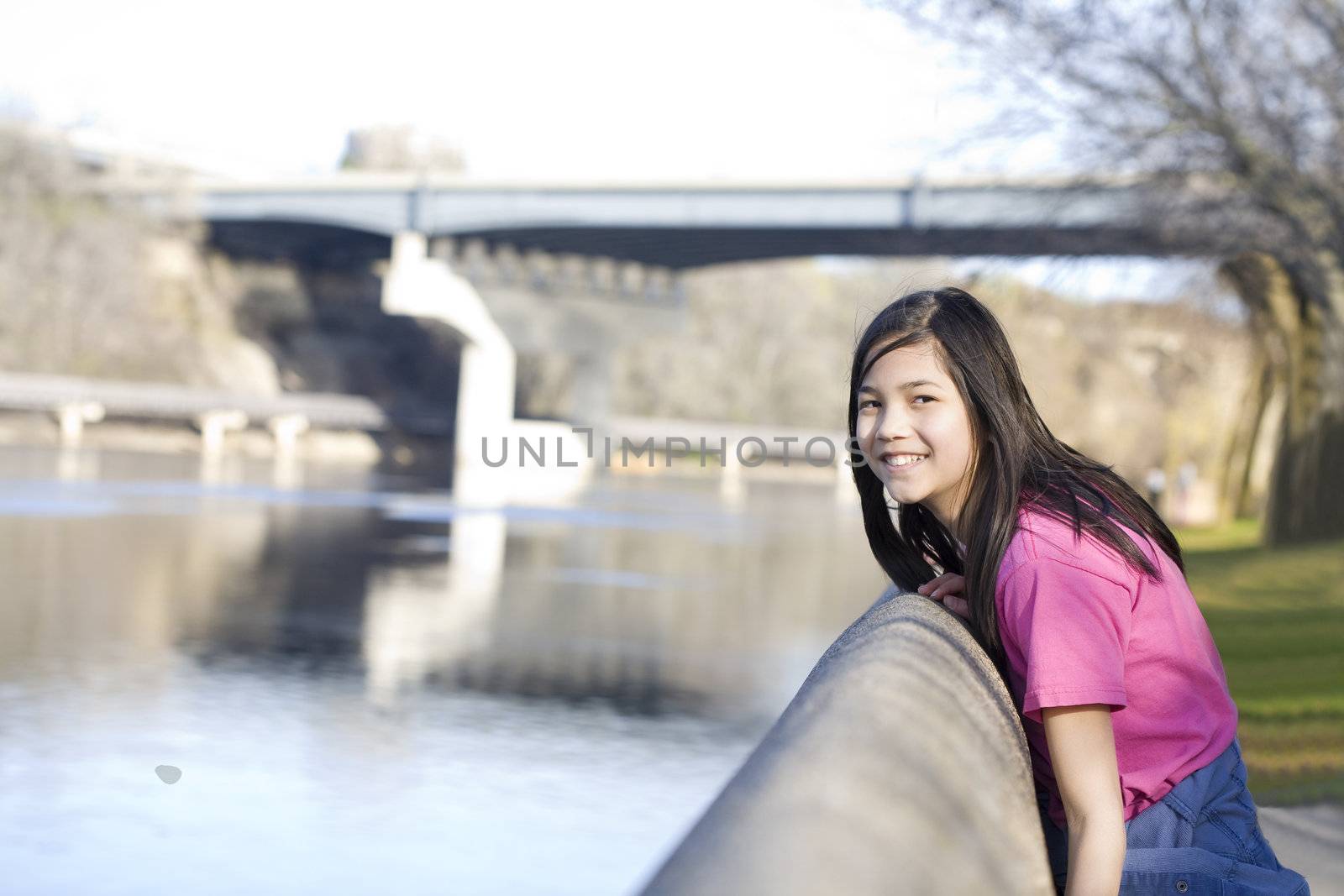 Young girl standing by bank of river in summer