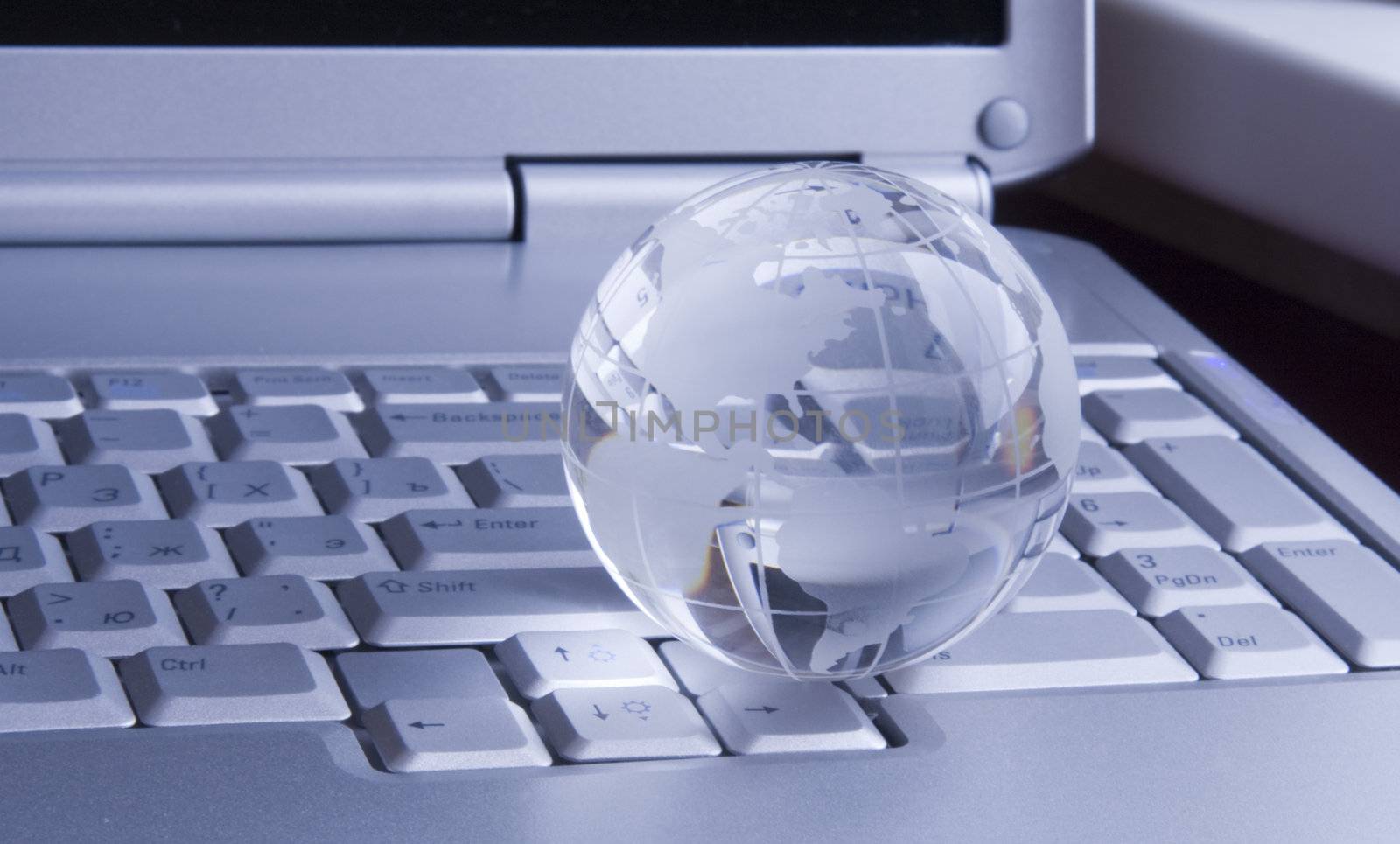 Crystal-glass globe on keyboard of  modern notebook. Background