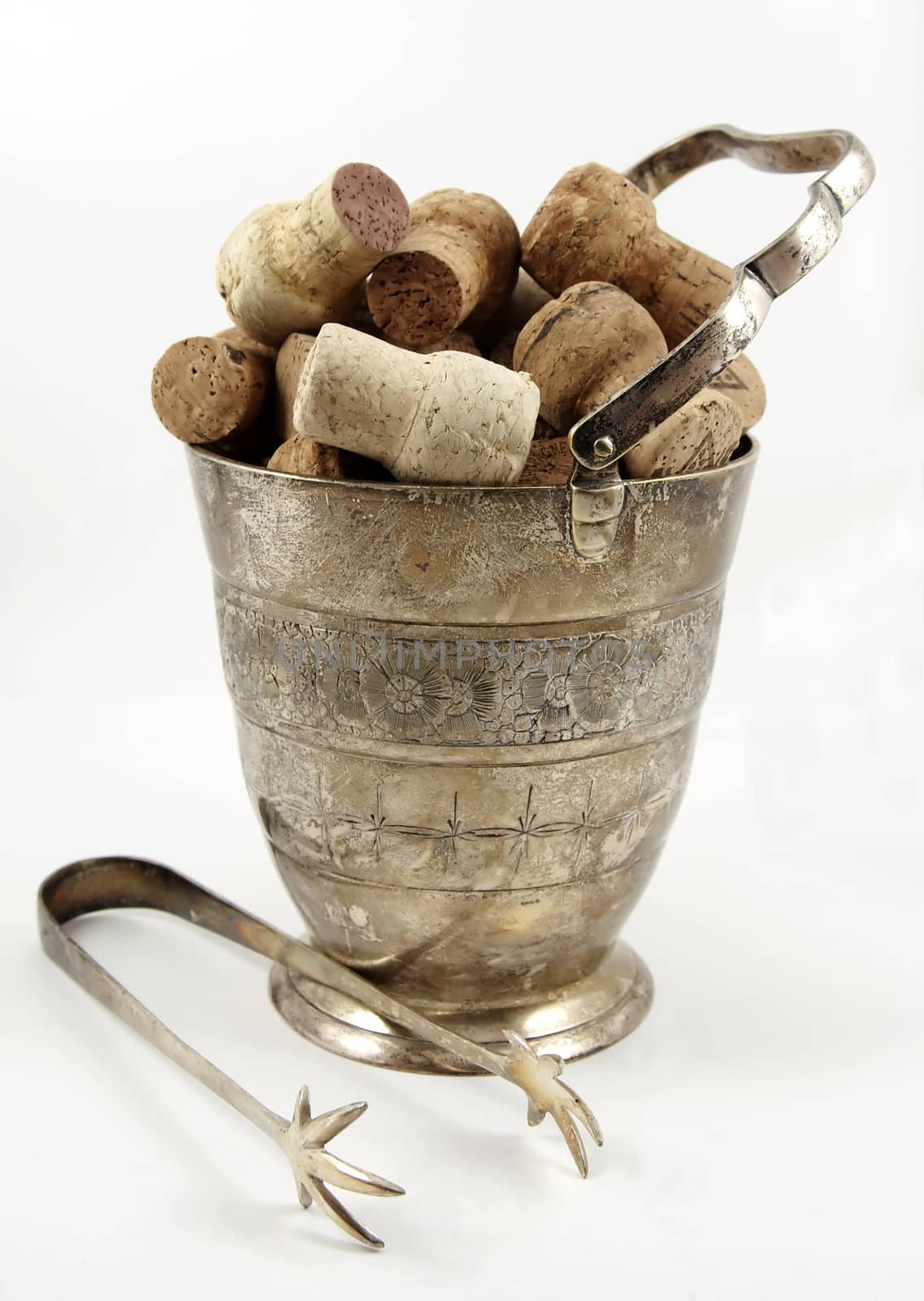 Ice tongs in front of bucket with champagne corks